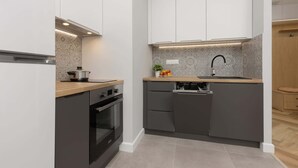 Una cocina compacta con horno integrado, un lavabo y lavavajillas.