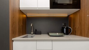 A compact kitchenette with a microwave, coffee maker, and a small sink. - Elegant Studio in Wola | Air Conditioning and Balcony (Warszawa)