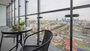 Ein Balkon mit Tisch und Stühlen, einem Blumentopf und Blick auf die Stadt.