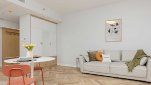 A modern living room with a sofa, a dining table with chairs, and a small side table.
