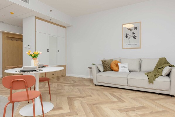 Ein modernes Wohnzimmer mit einer Couch, einem Esstisch mit Stühlen und einem kleinen Beistelltisch.