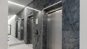 A modern elevator area with marble walls and a clean, tiled floor.