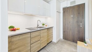 Una cocina moderna con armarios blancos, encimera de madera y pileta integrada.