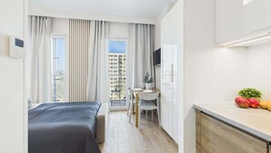 Una habitación de hotel moderna con una cama, un escritorio, una silla y una pequeña kitchenette.