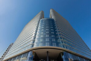 Un edificio de gran altura con fachada de vidrio curvada y dos torres simétricas.