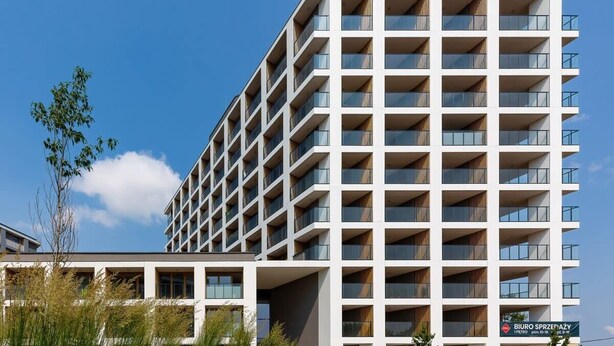 Ein modernes, mehrstöckiges Hotel mit einem Raster aus Balkonen und großen Fenstern.