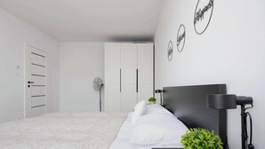 Un dormitorio con una cama, una mesita de noche con lámpara, una planta en maceta y una pared con tres letreros circulares.