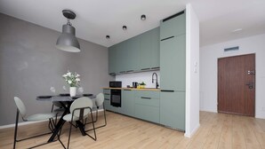 Una cocina moderna con armarios grises, una mesa de comedor con sillas e iluminación colgante.