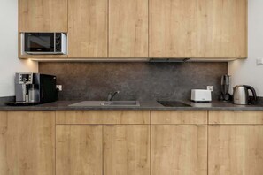 Eine moderne Küche mit Holzausstattung, einer eingebauten Mikrowelle, einer Kaffeemaschine, einem Toaster und einem Wasserkocher.