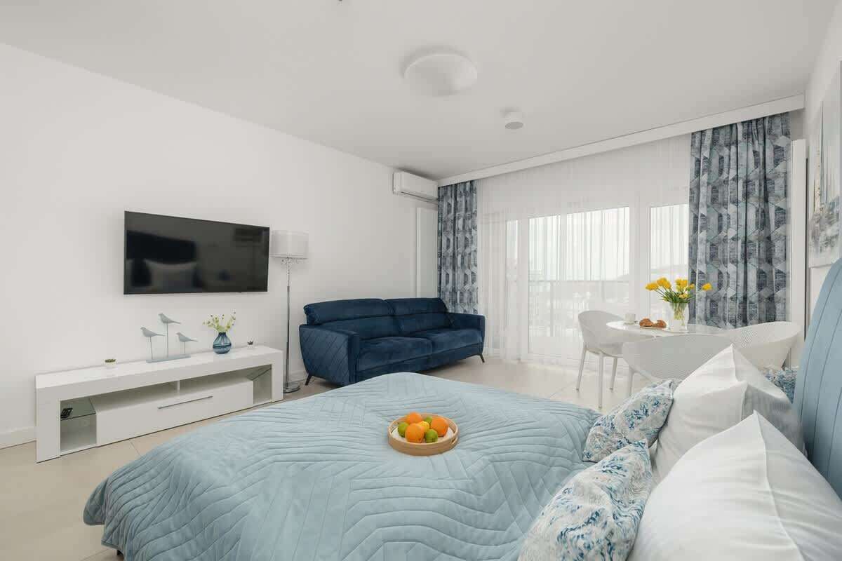 Une chambre moderne comprenant un lit, une télévision, un canapé, une table à manger et une fenêtre avec des rideaux.