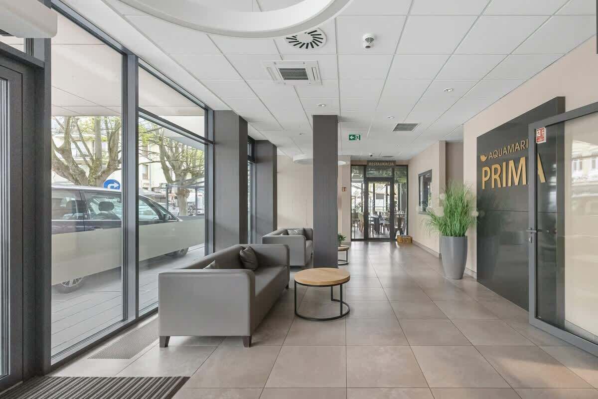A modern lobby with a reception desk, seating area, and a large window overlooking the street.