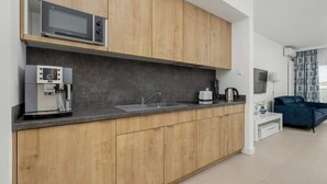 A modern kitchen with wooden cabinets, a built-in microwave, a coffee machine, and a sink.
