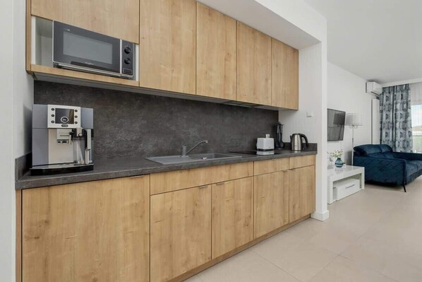 Eine moderne Küche mit Holzausstattung, einer eingebauten Mikrowelle, einer Kaffeemaschine und einem Spülbecken.
