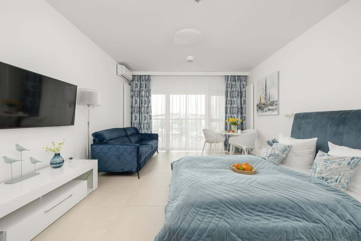 Ein modernes Schlafzimmer mit Bett, Sofa, Fernseher und Schreibtisch.