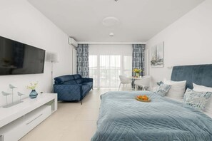 Ein modernes Schlafzimmer mit Bett, Sofa, Fernseher und Schreibtisch.