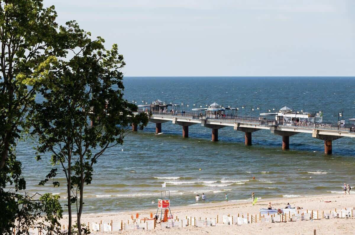 Eine Steg, der sich ins Wasser erstreckt, mit einem Strand im Vordergrund.