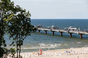 A pier extending into the water with a beach in the foreground.