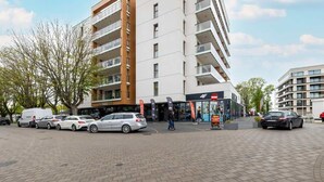 A modern multi-story building with a parking area in front.