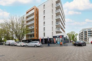 Ein modernes, mehrgeschossiges Gebäude mit Parkplatz davor.