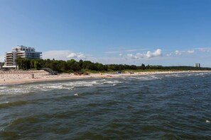 Ein Hotel an der Küste mit Blick auf einen Sandstrand und einem großen, mehrstöckigen Gebäude.