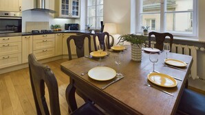 A well-lit kitchen with modern appliances, a dining table set for four, and large windows providing natural light. - Stylish Studio | Krakowskie Przedmieście, in the heart of Warsaw (Warszawa)