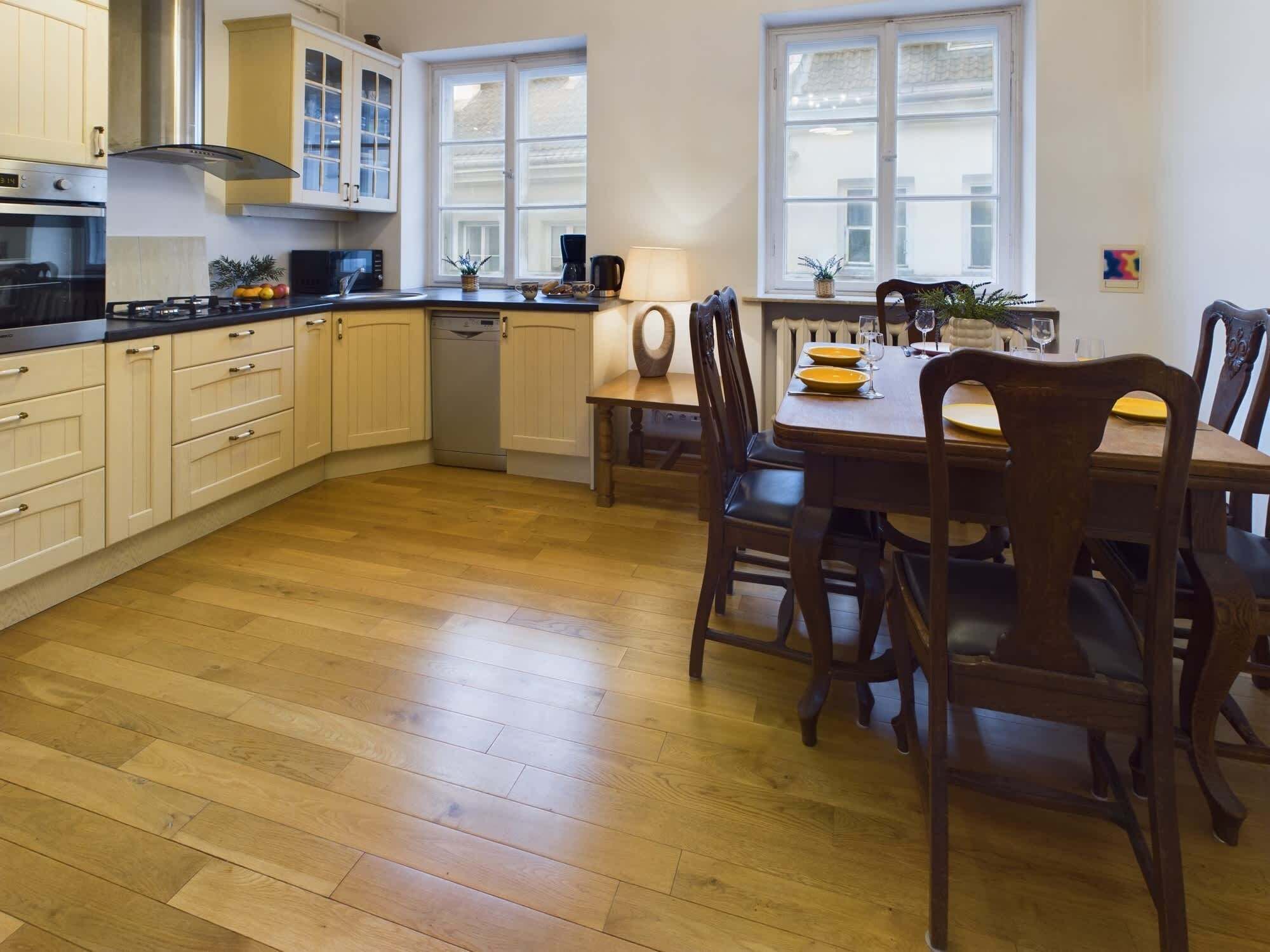 Una cocina moderna con armarios de madera, lavavajillas y un comedor con mesa y sillas.