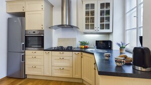 A modern kitchen with a built-in oven, a stainless steel range hood, and a microwave. - Stylish Studio | Krakowskie Przedmieście, in the heart of Warsaw (Warszawa)