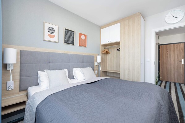 Ett modernt hotellrum med en stor säng, en garderob och en väckarklocka på väggen.
