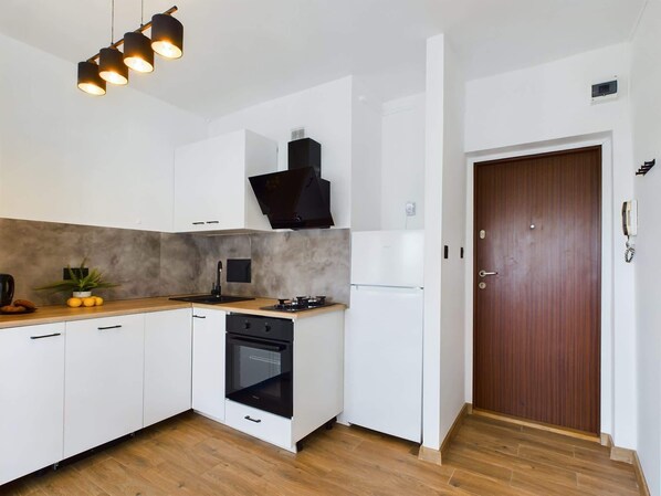 Una cocina moderna con armarios blancos, una estufa negra y una encimera de madera.
