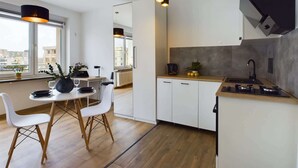 Eine moderne Küche mit weißen Schränken, einer Holz Arbeitsplatte und einem schwarzen Herd. Es gibt einen Essbereich mit einem weißen Tisch und Stühlen, sowie ein großes Fenster, das für natürliches Licht sorgt.