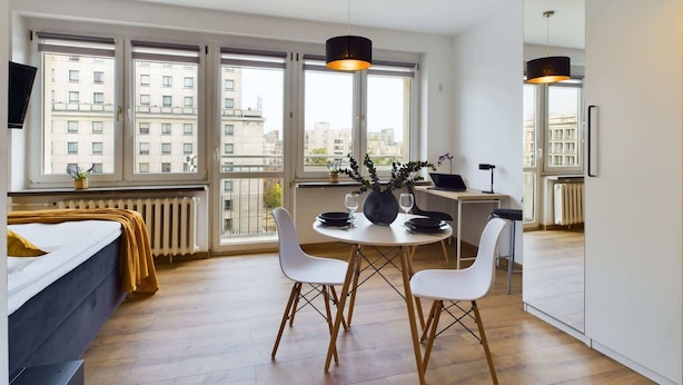 Ein modernes Apartment mit Essbereich, einem Bett und großen Fenstern mit Blick auf die Stadt.