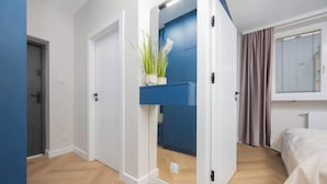 A modern bedroom with a bed, a blue wardrobe, and a potted plant. - Stylish Apartment in the Center | Workplace (Warszawa)