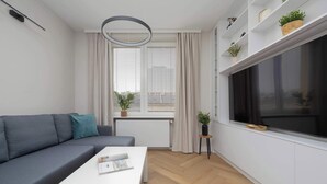 A modern living room with a gray sofa, a white coffee table, and a large window with curtains. - Stylish Apartment in the Center | Workplace (Warszawa)