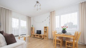 Una sala de estar con sofá, mueble para televisión, mesa de comedor de madera y sillas.