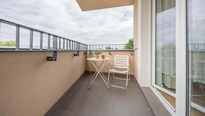 Un balcón con mesa y sillas, una planta en maceta y vistas de la ciudad.