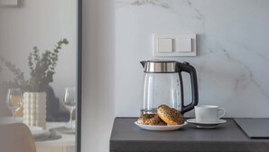 Eine moderne Küche mit Marmor-Spritzschutz, einer Kaffeemaschine, einem Tablett mit Gebäck und einer weißen Tasse auf der Arbeitsplatte.