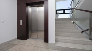 Un ascenseur moderne et un escalier avec des rampes en verre.