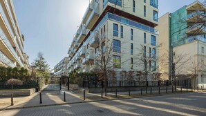 Un immeuble d’appartements moderne doté de nombreux balcons, d’une entrée sécurisée et d’un chemin piétonnier dallé.