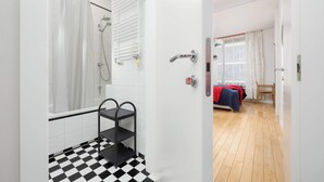 Une salle de bain moderne avec un carrelage à motifs géométriques, une douche et une étagère en métal.