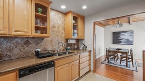 A kitchen with wooden cabinets, a dishwasher, and a dining area with a table and chairs.