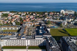 A high-rise hotel with multiple floors, a parking area, and a view of the sea.