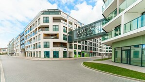 Un hotel moderno con una entrada destacada, varios balcones y un cielo despejado.
