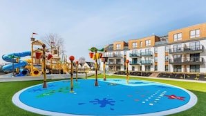 Un parque infantil con toboganes y estructuras de escalada, rodeado de modernos edificios residenciales.