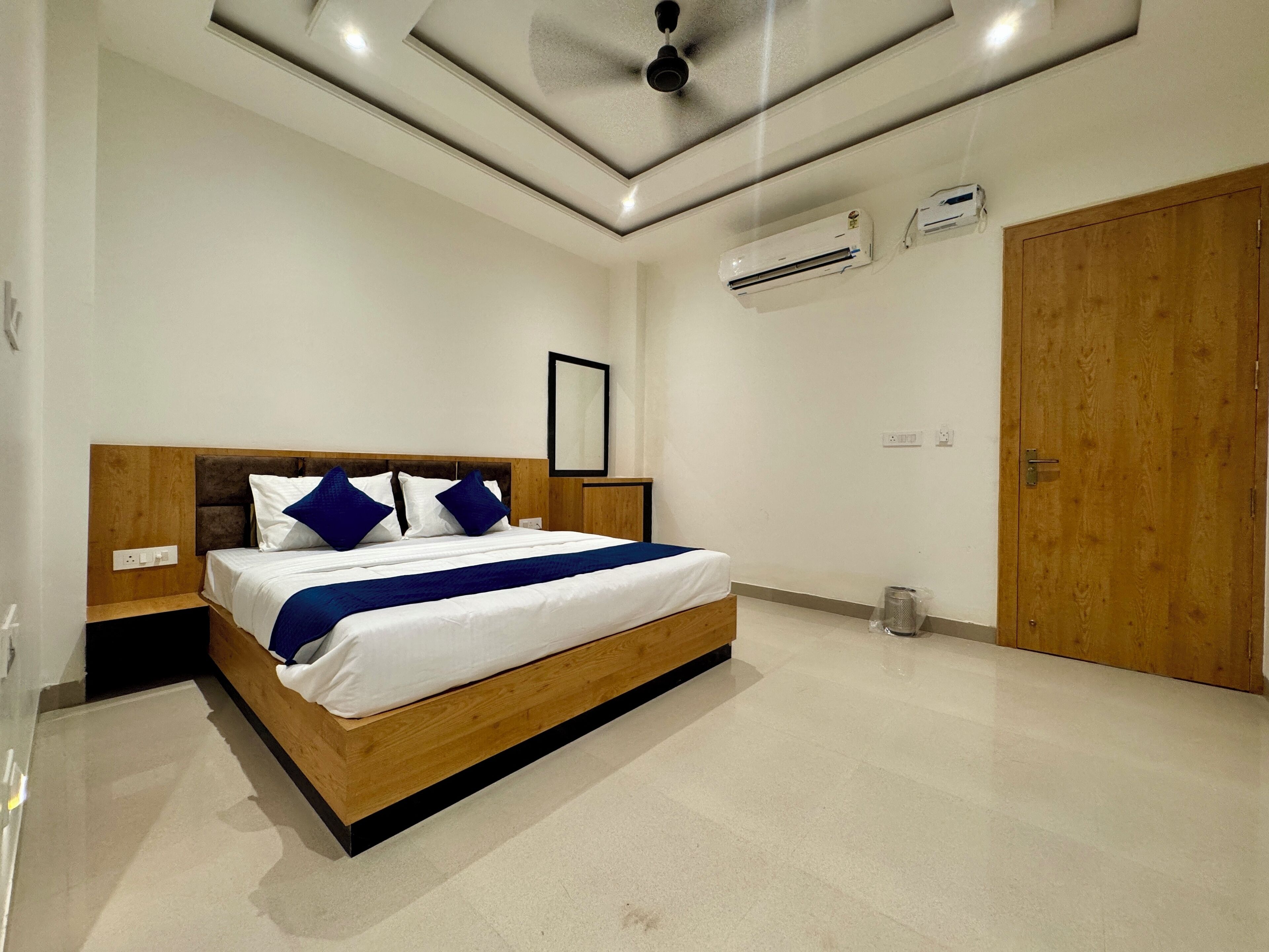 A modern bedroom with a wooden bed frame, white bedding, and a blue accent.