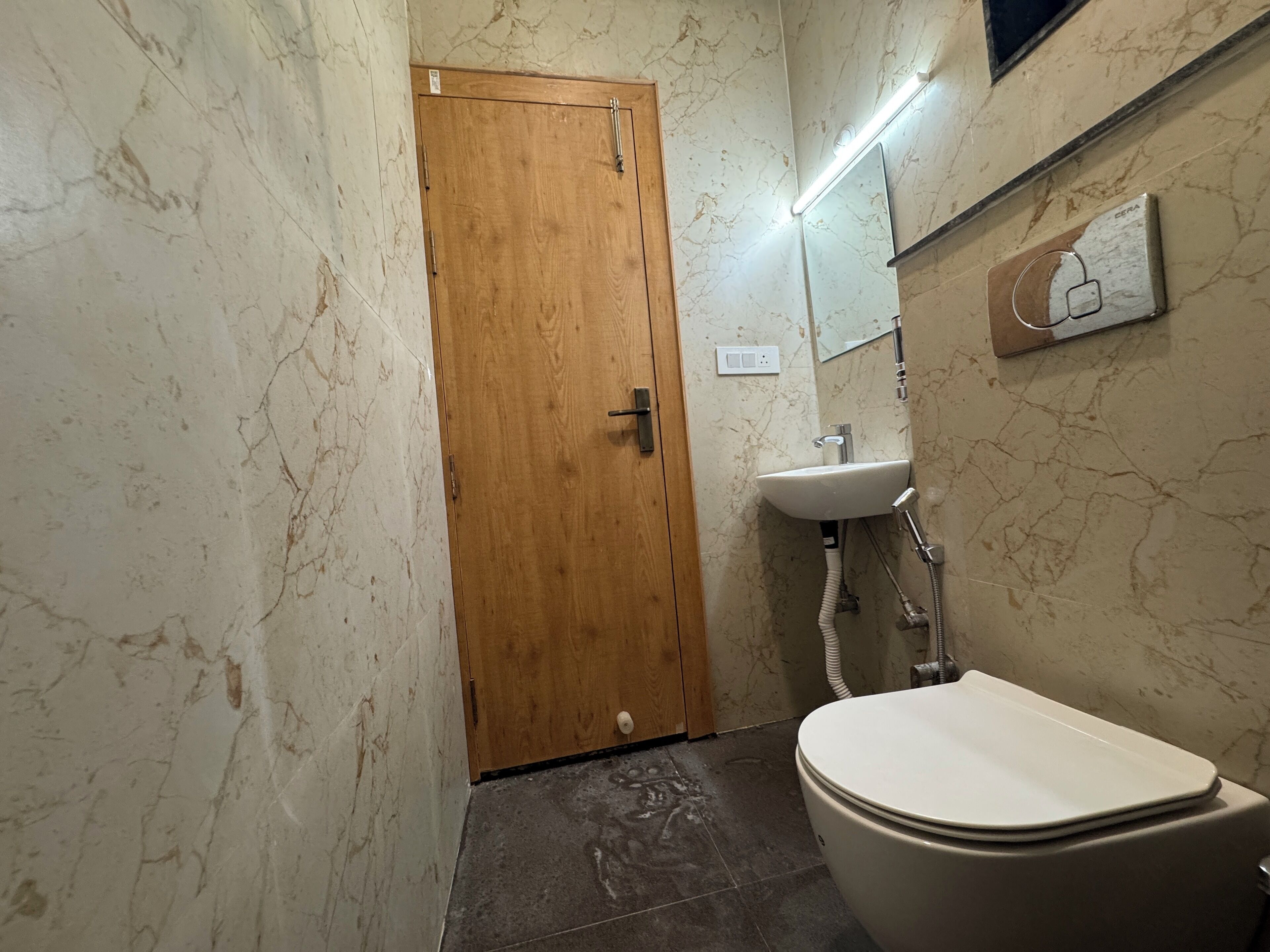 A bathroom with a wooden door, a white sink, and a toilet.
