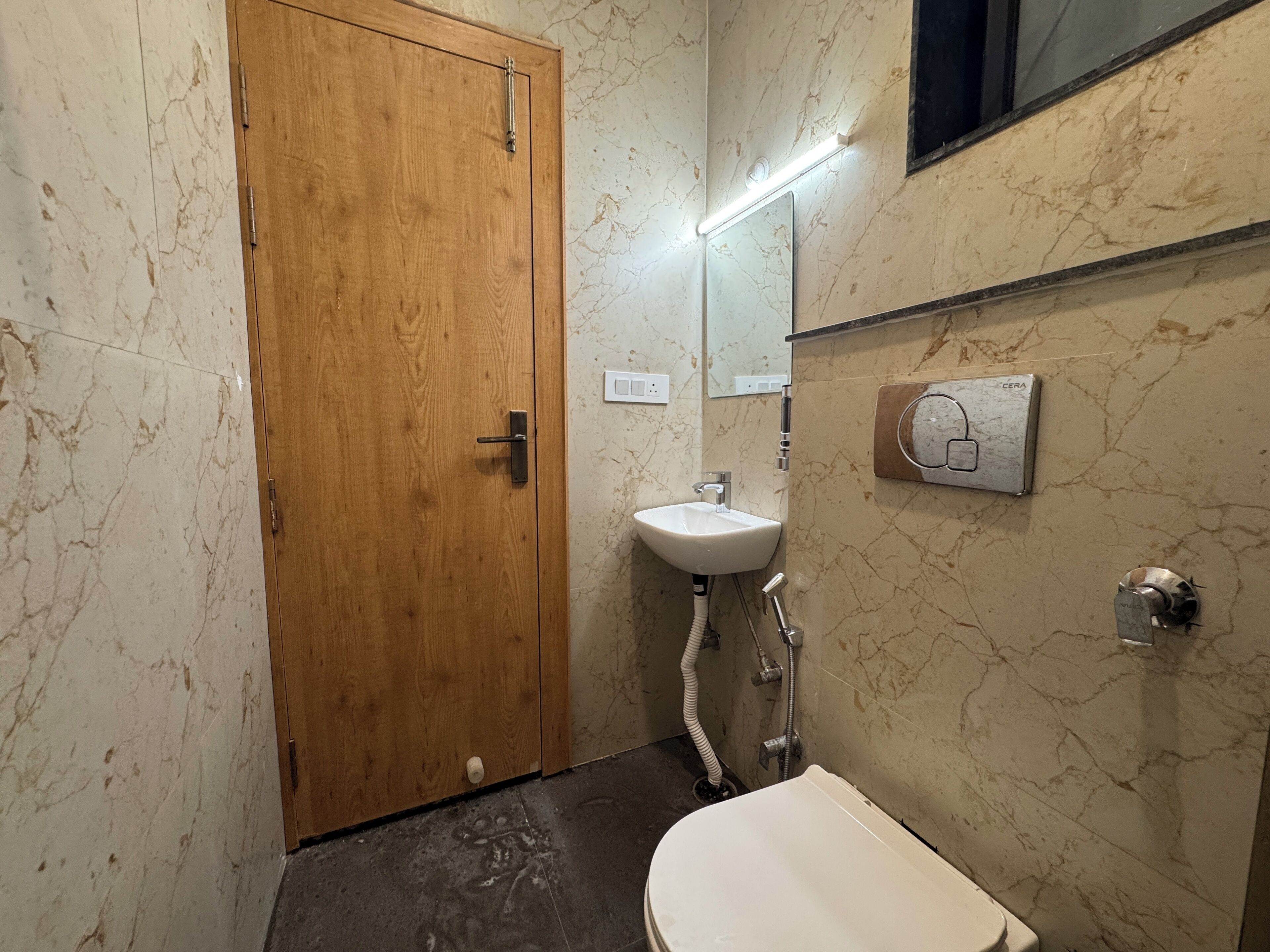 Un bagno con una porta in legno, un lavandino bianco, uno specchio e uno scaldacqua Cera.