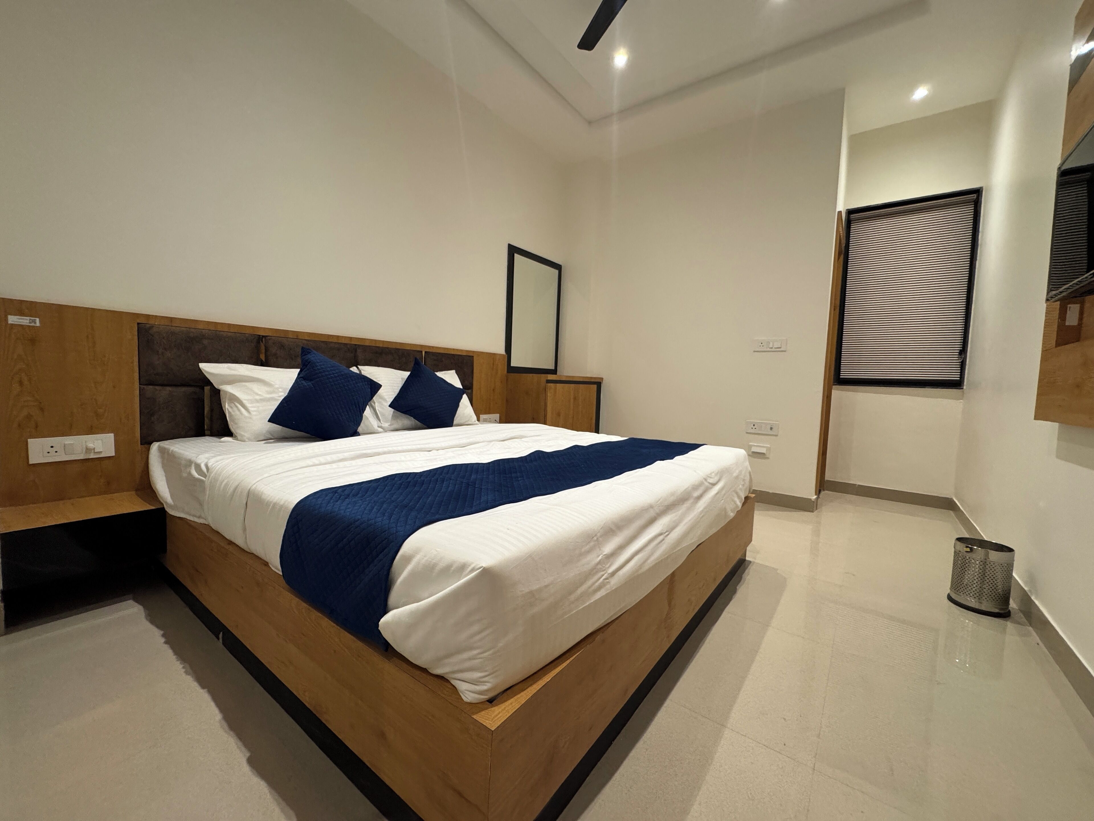 Ein modernes Schlafzimmer mit einem hölzernen Bettgestell, weißer Bettwäsche und blauen Akzenten.