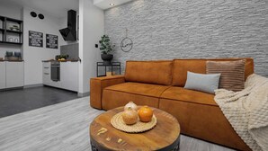 A modern living room with a sofa, coffee table, and kitchen in the background.