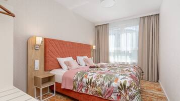 Een hotelkamer met een groot bed, een nachtkastje, een wandlamp en een raam met gordijnen.