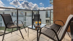 A balcony with two chairs, a table, and a glass partition.
